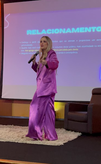 Tinara Fava palestrando no palco durante uma apresentação TEDx